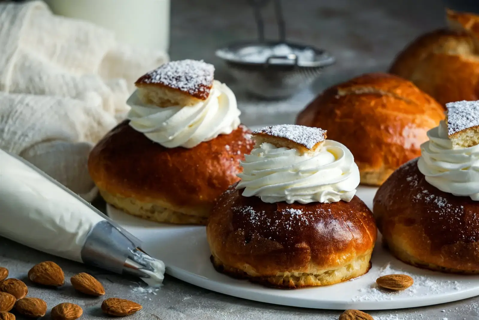 Fresh semlor with whipped cream and powdered sugar on a serving plate