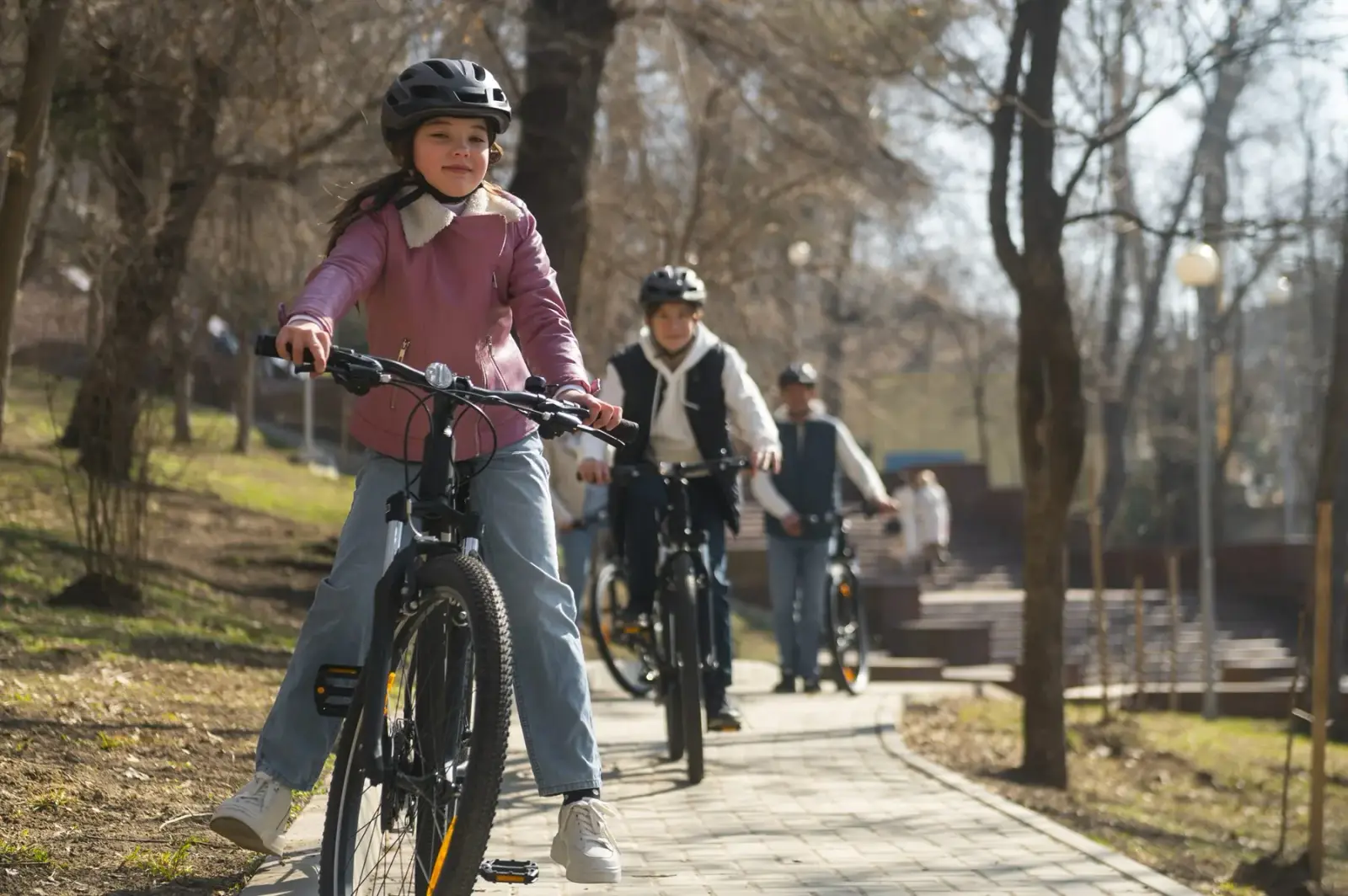 Family cycling together along a tree-lined path in Stockholm during spring