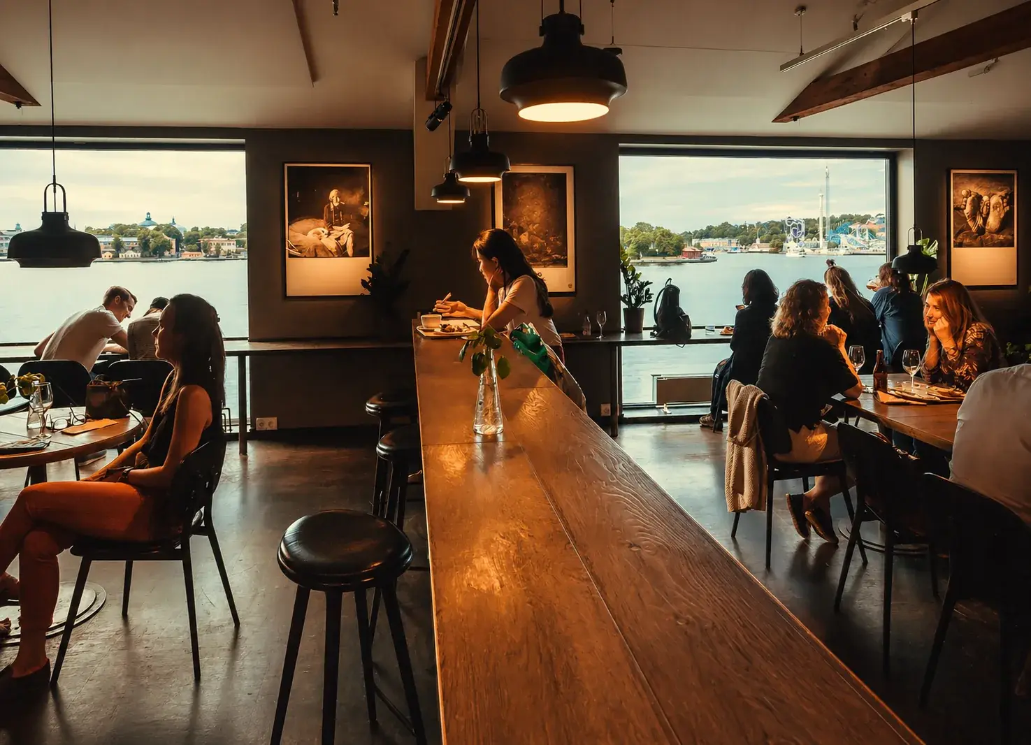 Inside Fotografiska's bistro with diners seated beside large windows overlooking Stockholm's waterfront