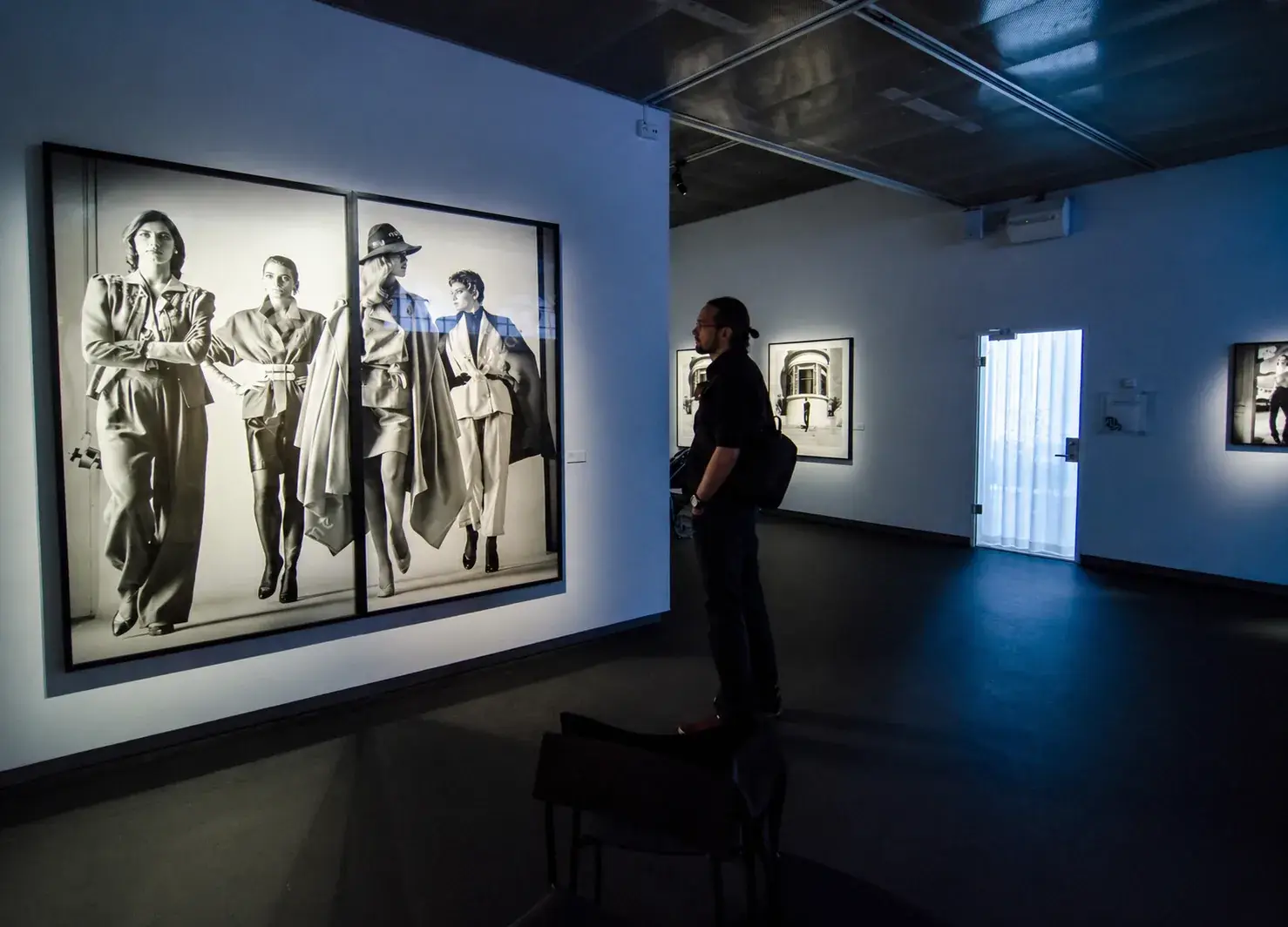 Visitor standing in a dark Fotografiska gallery beside a large black-and-white photograph