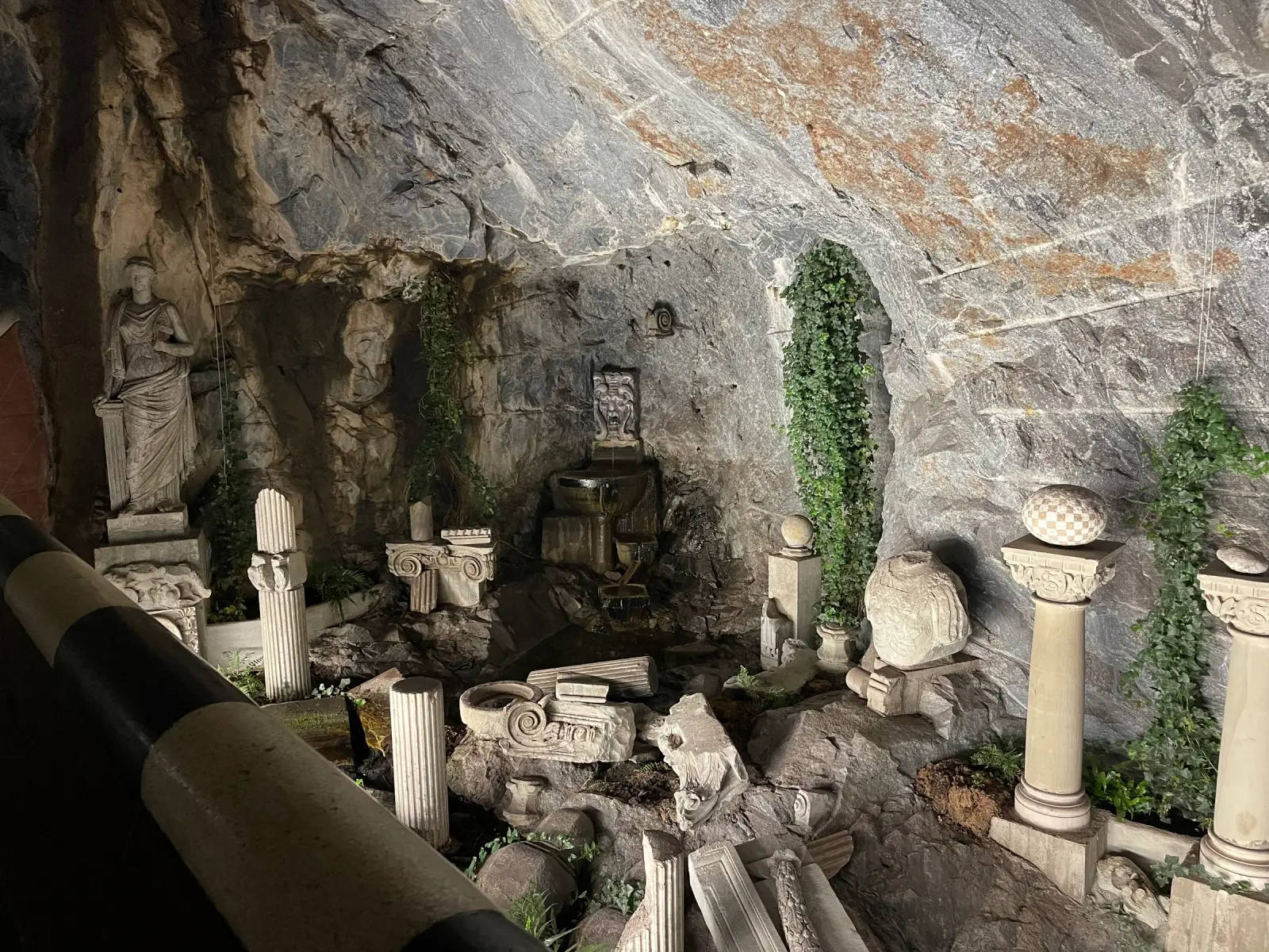 Classical sculptures, stone fragments, and greenery inside Kungsträdgården subway station