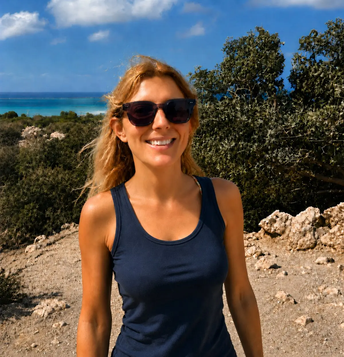 Sara Bulgheroni smiling by a Mediterranean seaside landscape