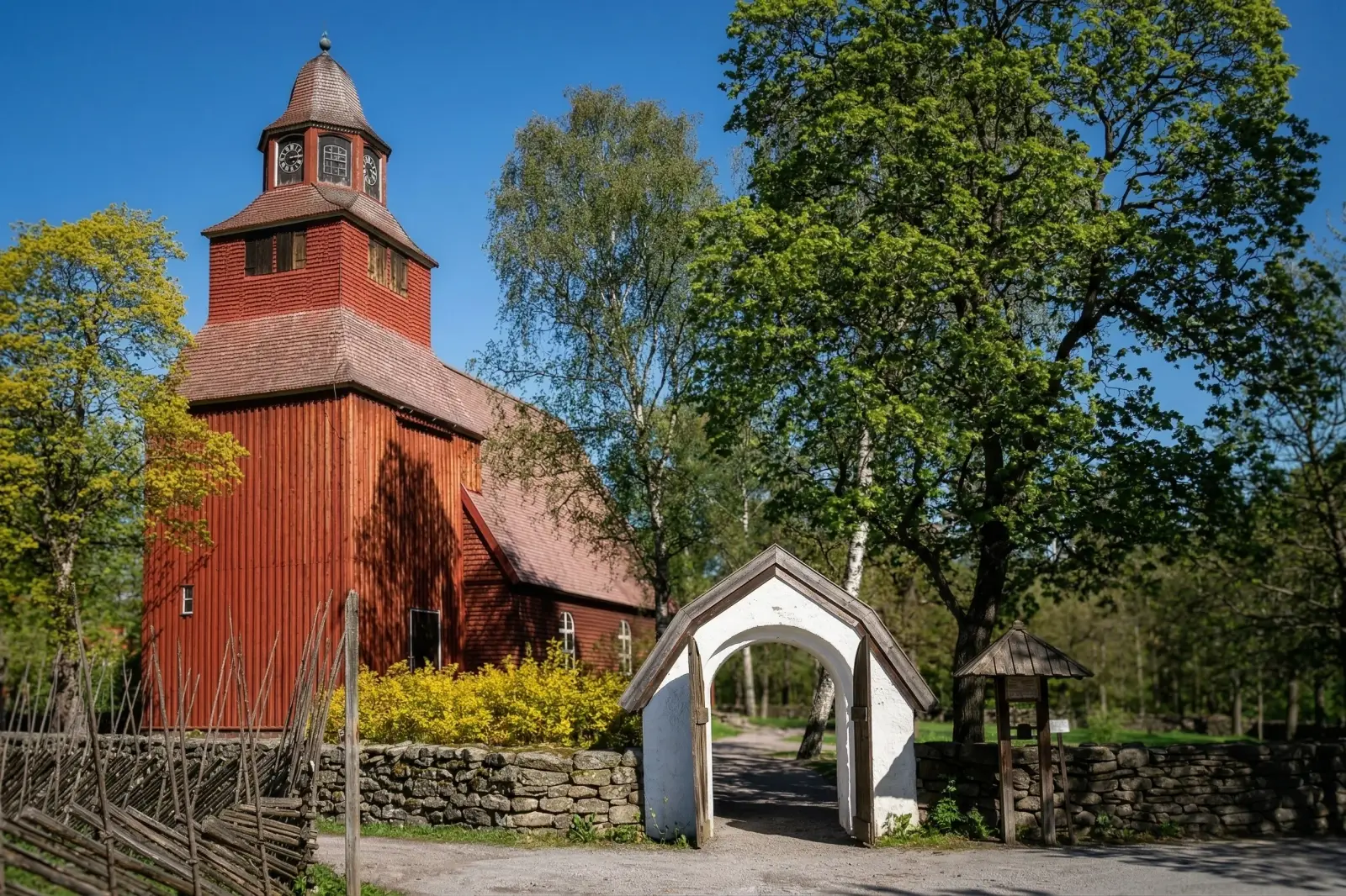 Seglora Church at Skansen with its white gate and stone wall on a bright spring day
