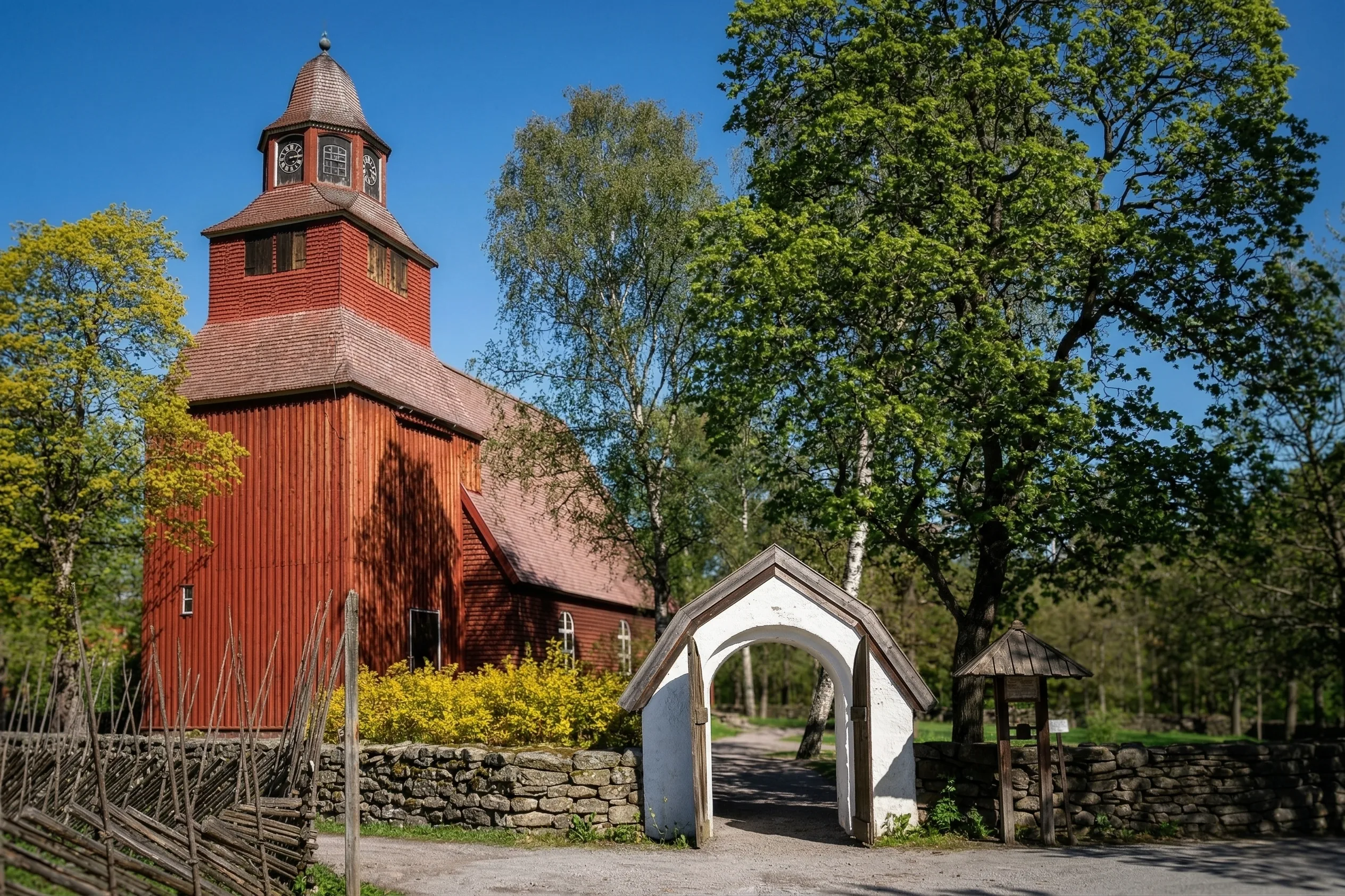 Seglora Church at Skansen with its white gate and stone wall on a bright spring day