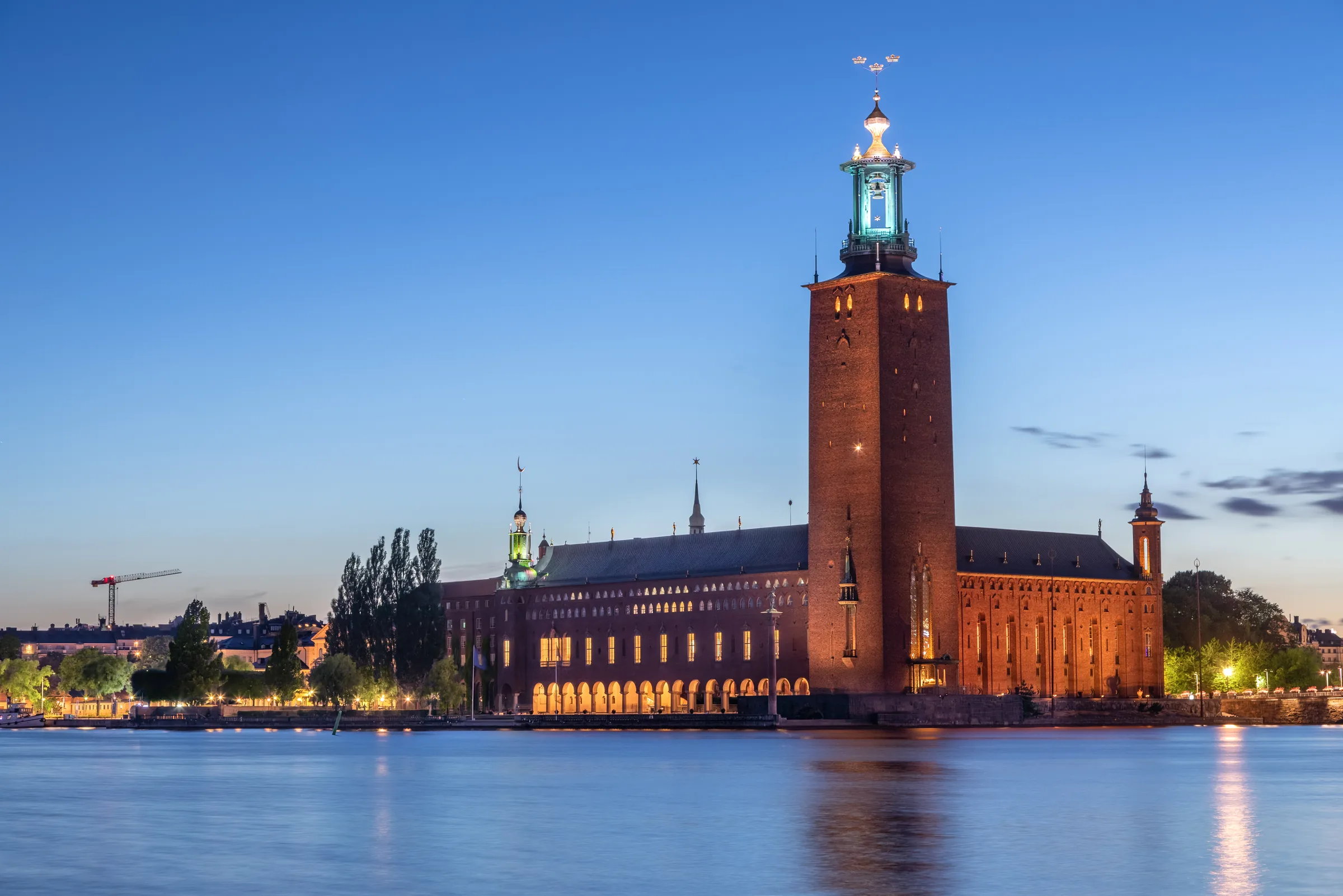 Blue-hour waterfront view beside the Royal Palace with warm lights reflecting across central Stockholm