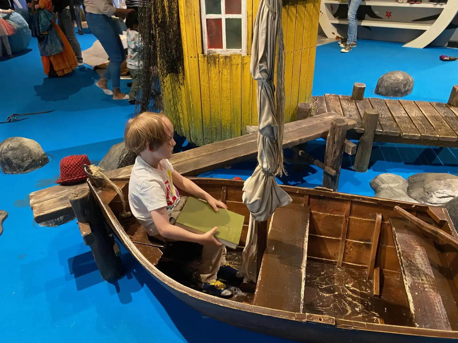 Child sitting in a wooden play boat inside Junibacken in Stockholm