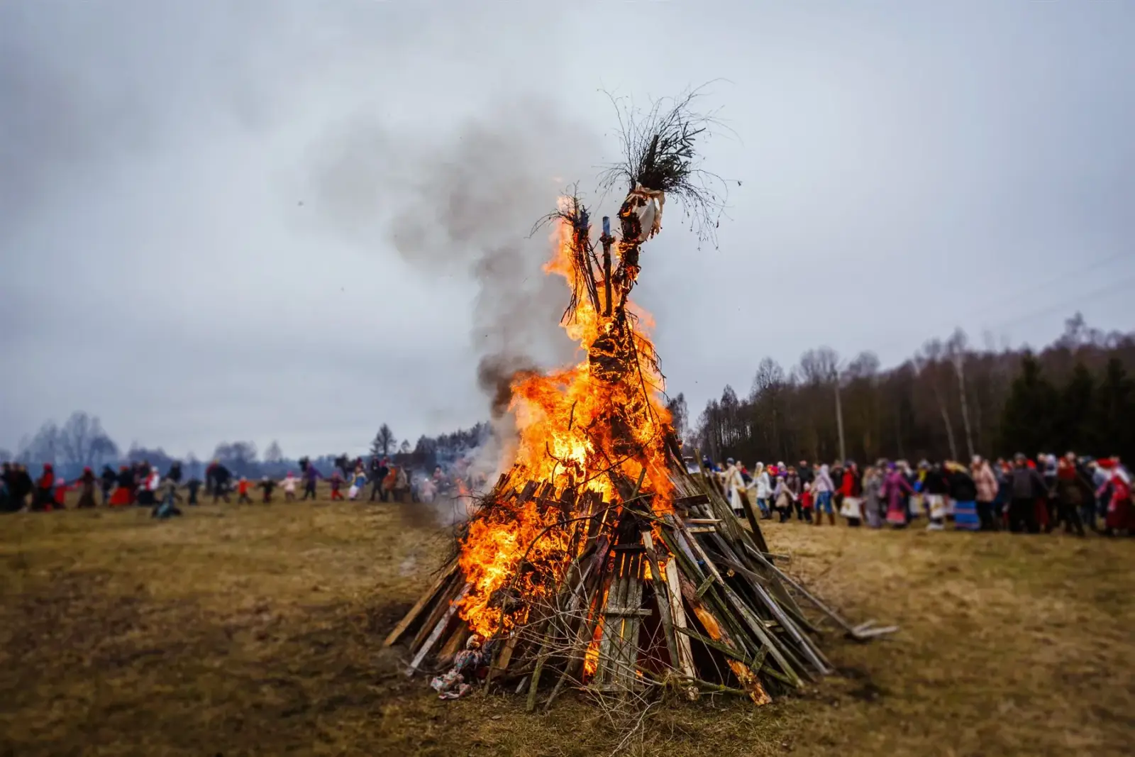 Traditional Valborg bonfire burning in an open field with people gathered around