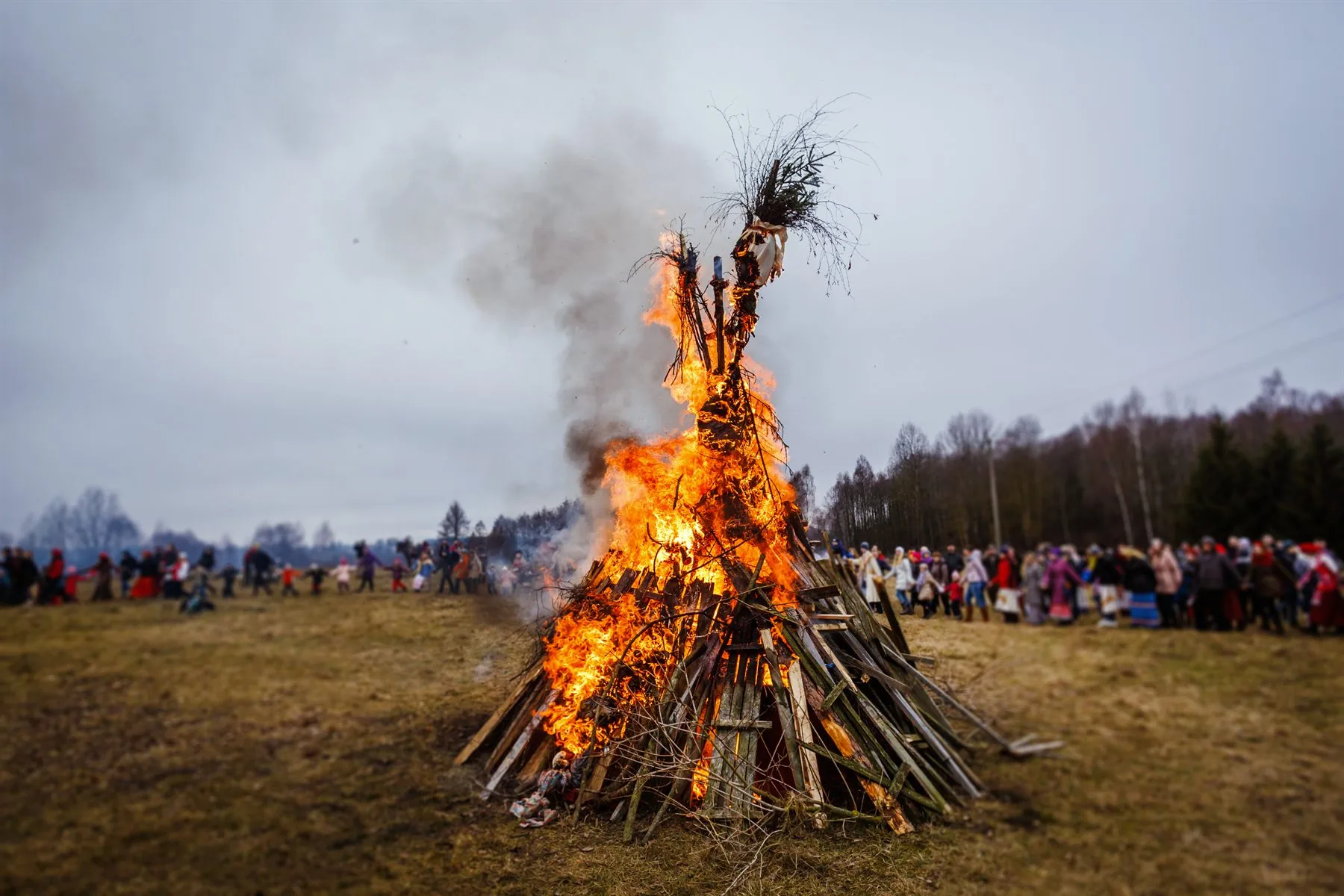 Traditional Valborg bonfire burning in an open field with people gathered around