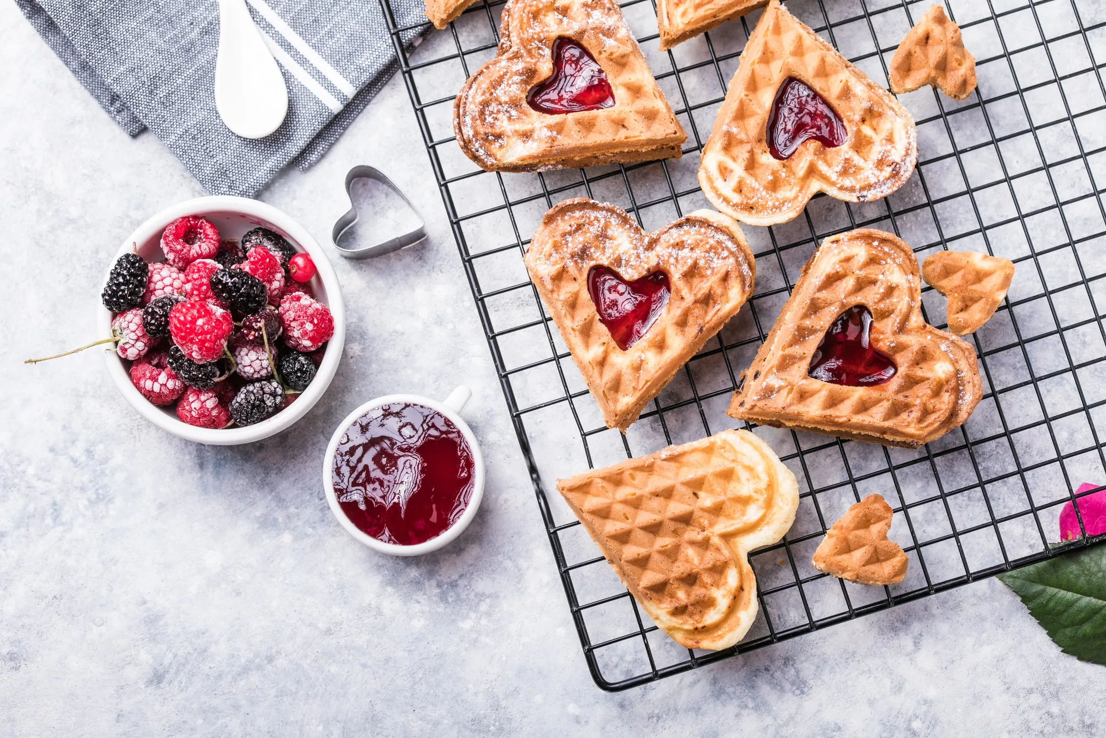Heart-shaped Swedish waffles dusted with sugar and topped with red berries on a serving tray