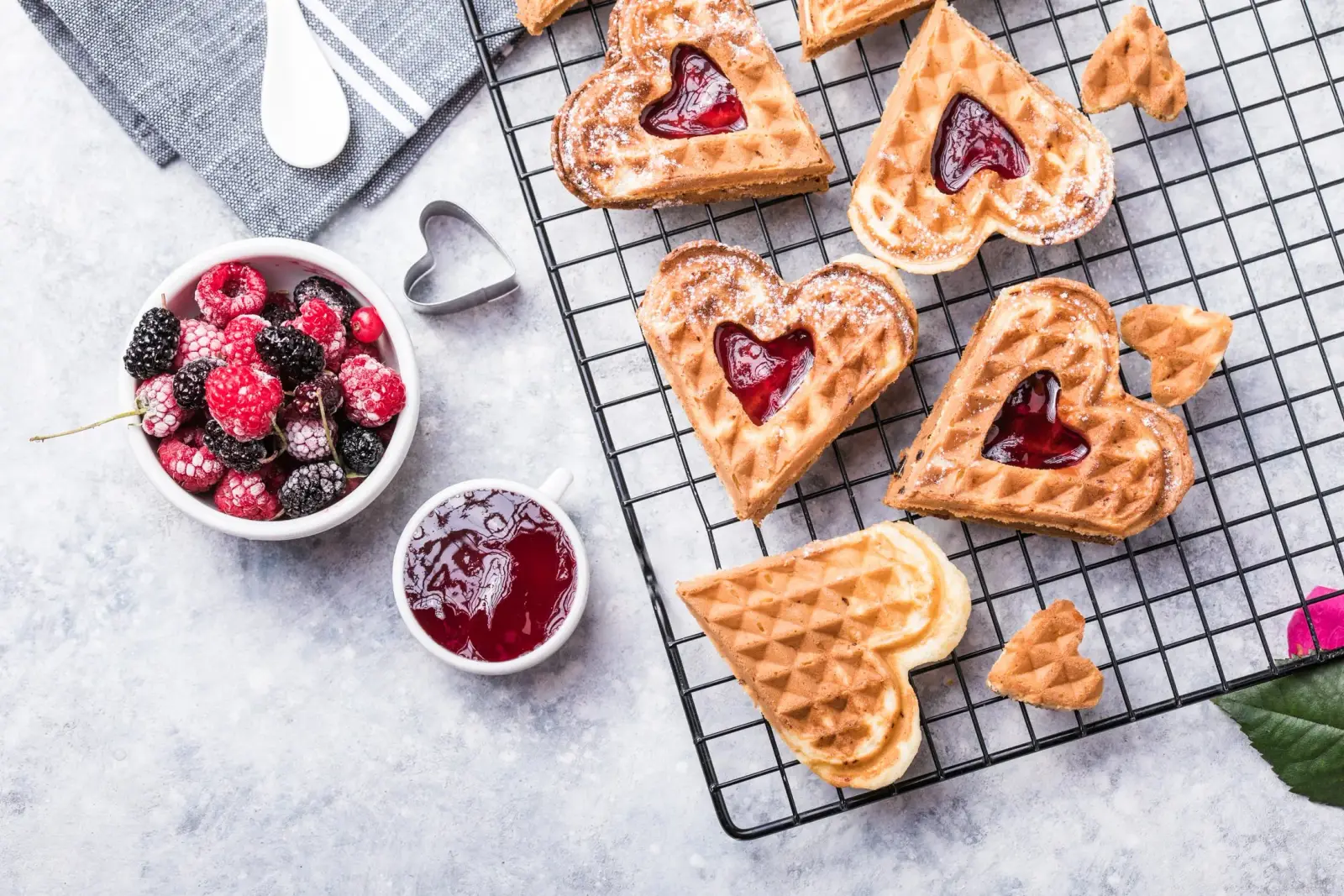 Heart-shaped Swedish waffles dusted with sugar and topped with red berries on a serving tray