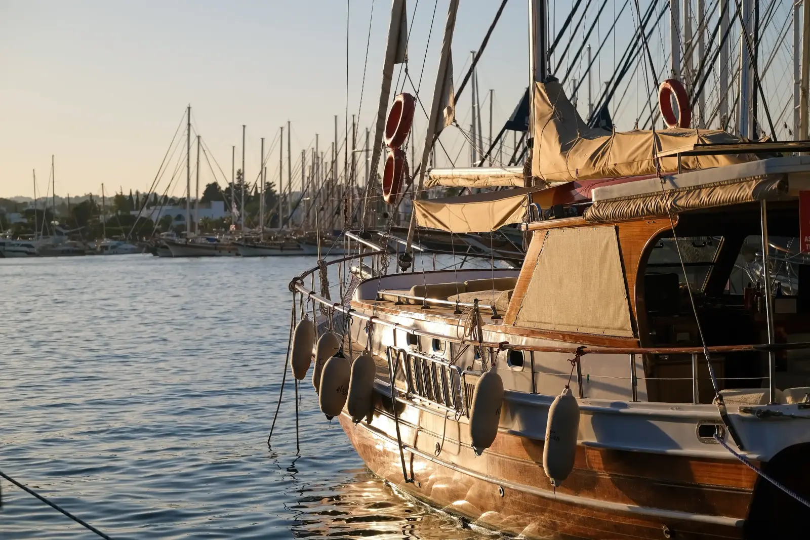Classic wooden boat moored in warm evening light beside a marina